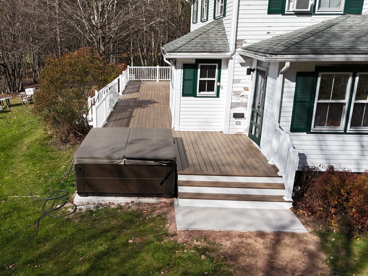 Finished deck with steps down to a concrete landing next to the hot tub